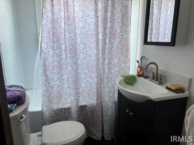 full bathroom featuring toilet, vanity, and shower / tub combo with curtain