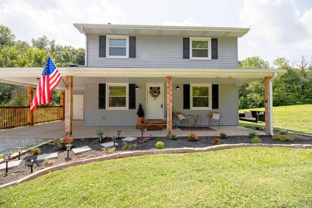 view of property featuring covered porch, a carport, and a front yard