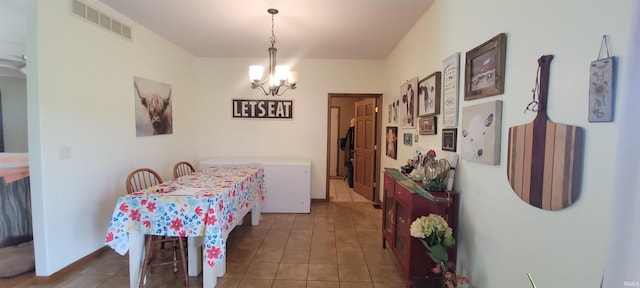 dining area with a chandelier and dark tile patterned floors