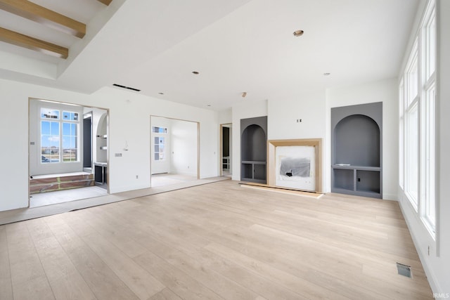 unfurnished living room with beam ceiling and light hardwood / wood-style flooring