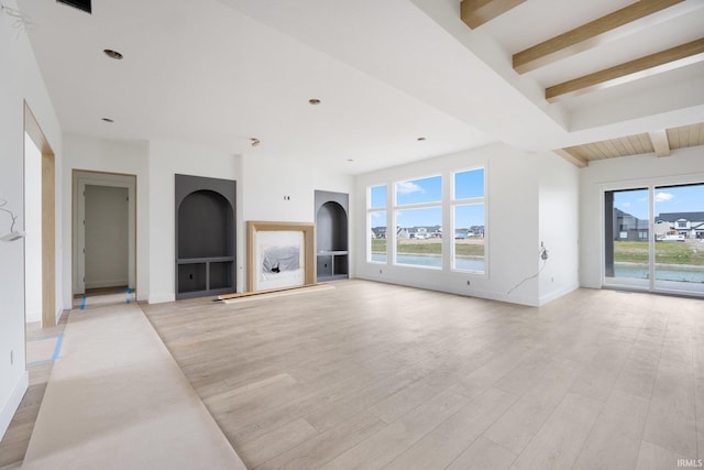 unfurnished living room with beam ceiling, light wood-type flooring, and a wealth of natural light