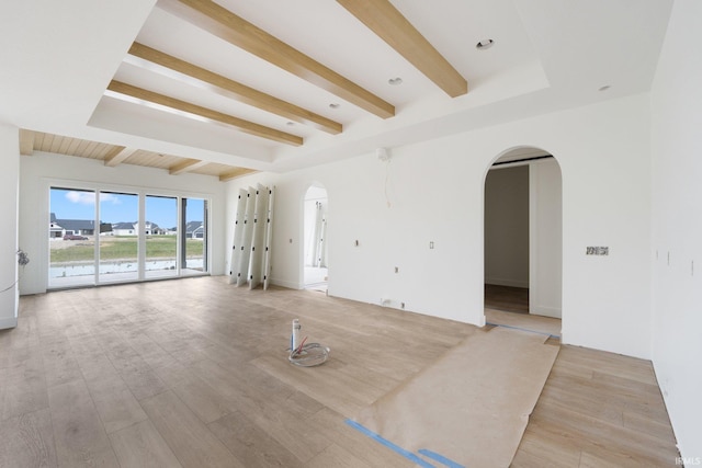 unfurnished living room with beam ceiling and light wood-type flooring