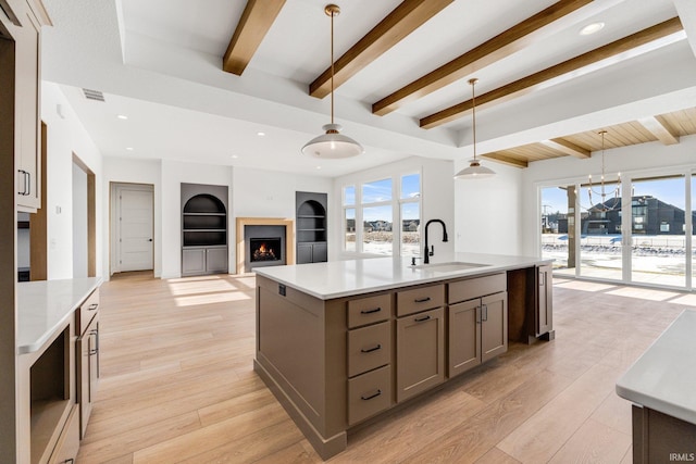 12279 Blue Jay Trl, Fort Wayne, IN 46814 - kitchen featuring gray cabinetry, a lit fireplace, light countertops, decorative light fixtures, and beamed ceiling