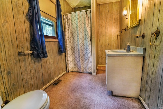 bathroom with vanity, wooden walls, and toilet