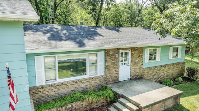 view of front of home featuring brick siding and a shingled roof