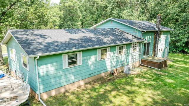 rear view of house with central air condition unit and a lawn