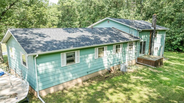 exterior space featuring central air condition unit, a lawn, a chimney, and a shingled roof