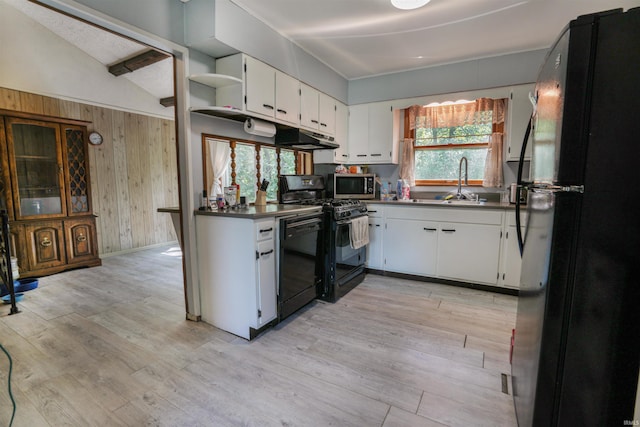 kitchen featuring lofted ceiling, light hardwood / wood-style flooring, white cabinets, black appliances, and a healthy amount of sunlight