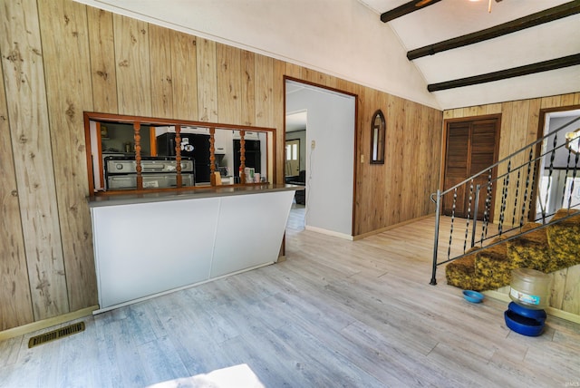 interior space with wood walls, light hardwood / wood-style flooring, and lofted ceiling with beams