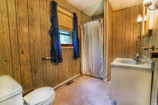 bathroom with vanity, wood walls, a textured ceiling, and toilet