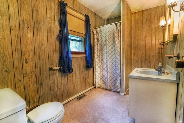 full bathroom featuring wooden walls, a textured ceiling, toilet, and vanity