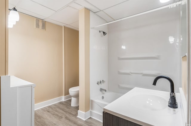 full bathroom featuring a paneled ceiling, vanity, wood-type flooring, shower / bathtub combination, and toilet