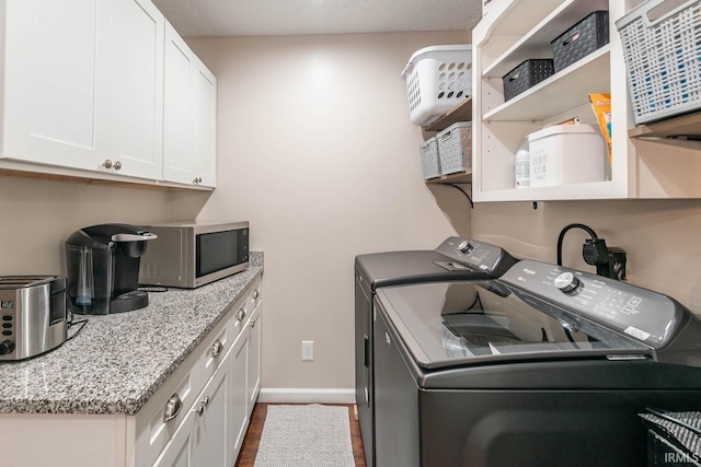 laundry area with dark wood-type flooring, washer and dryer, and cabinets