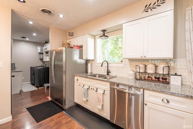 kitchen with sink, white cabinetry, stainless steel appliances, and independent washer and dryer