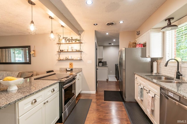 kitchen featuring white cabinetry, appliances with stainless steel finishes, decorative light fixtures, light stone counters, and sink