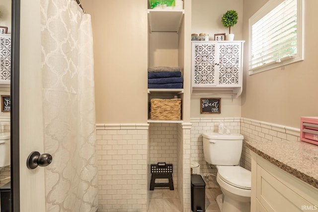 bathroom with toilet, vanity, tile walls, and tile patterned floors