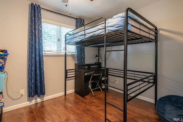 bedroom with ceiling fan, dark wood-type flooring, and a textured ceiling