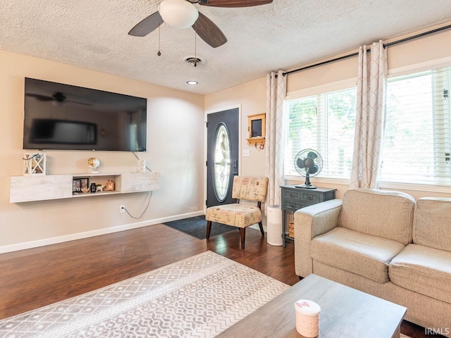 living room with ceiling fan, a textured ceiling, and dark hardwood / wood-style floors