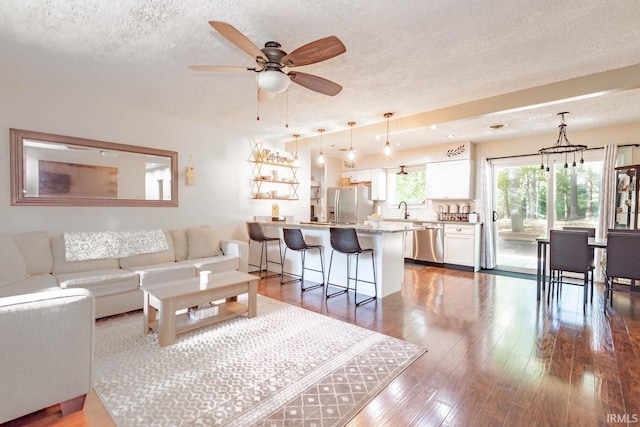 living room featuring a textured ceiling, ceiling fan, hardwood / wood-style flooring, and sink