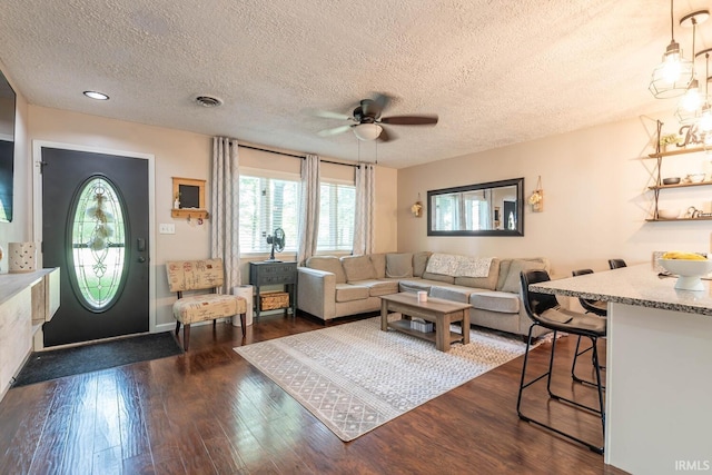 living room with ceiling fan, a textured ceiling, and dark hardwood / wood-style flooring