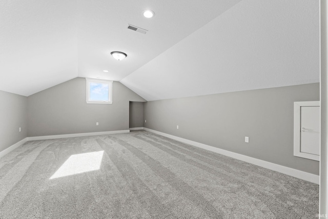 additional living space featuring visible vents, baseboards, lofted ceiling, and carpet