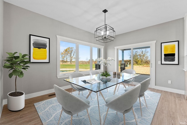 dining space with a notable chandelier and light hardwood / wood-style flooring