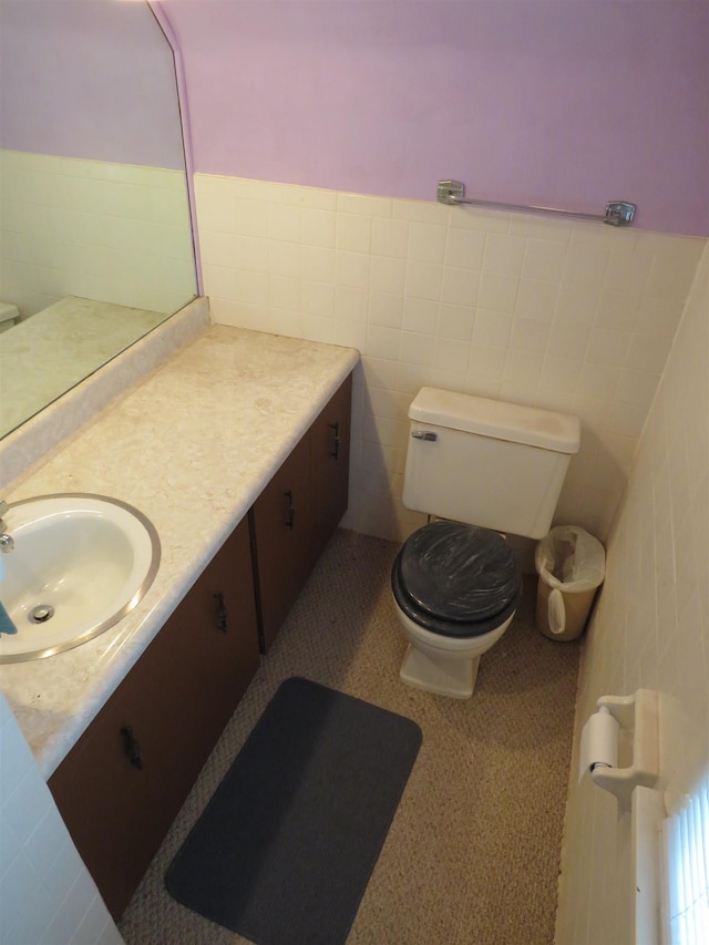 bathroom featuring vanity, toilet, and tile walls