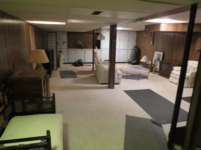 basement with wood walls, carpet, and a paneled ceiling