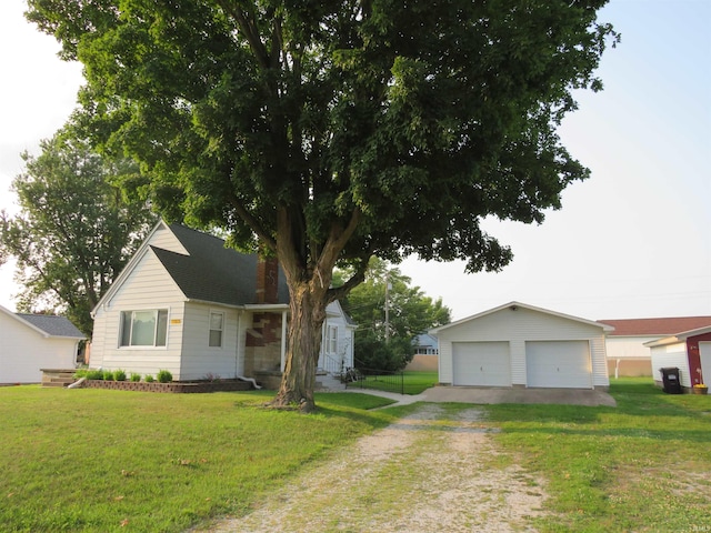 view of front of house featuring a garage, a front lawn, and an outbuilding