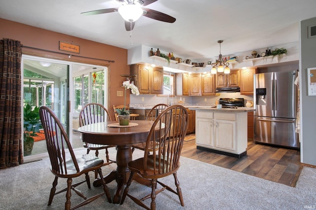 dining space with dark colored carpet and ceiling fan with notable chandelier