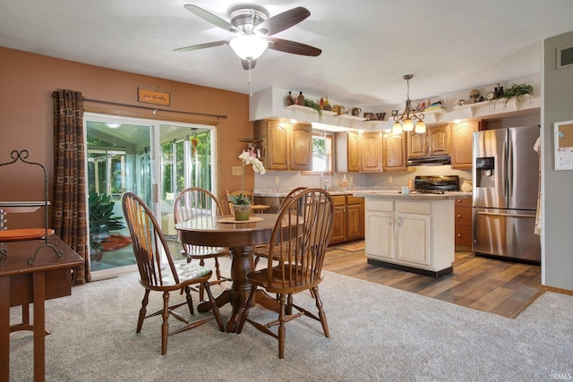 dining area with ceiling fan with notable chandelier and light hardwood / wood-style floors