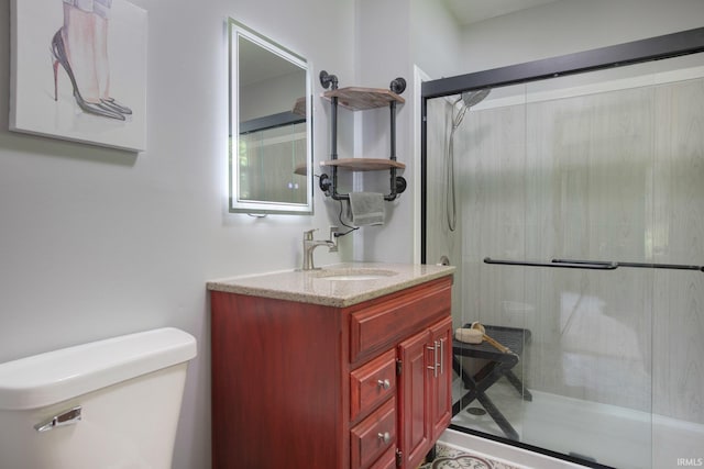 bathroom with vanity, toilet, and a shower with door