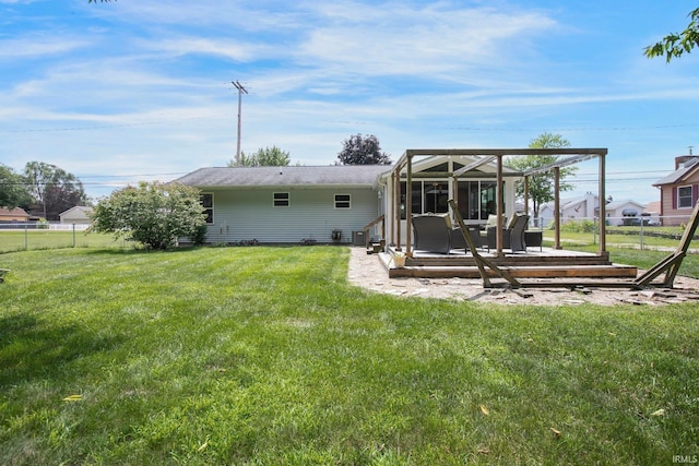 rear view of property with a sunroom, a wooden deck, and a lawn