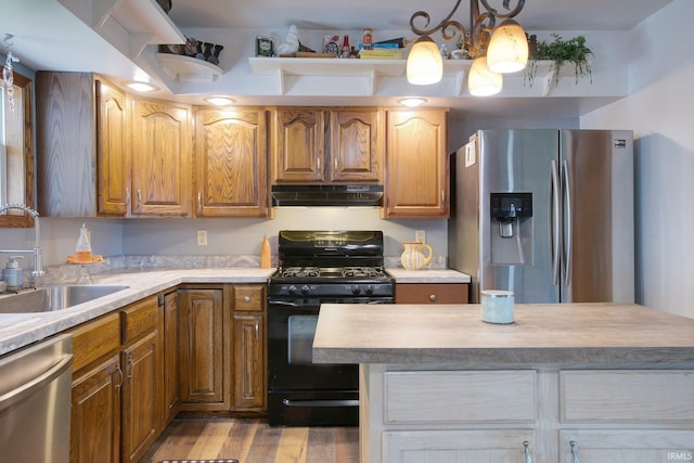 kitchen with light hardwood / wood-style floors, sink, hanging light fixtures, and appliances with stainless steel finishes