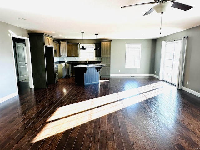 kitchen featuring dark hardwood / wood-style flooring, a kitchen breakfast bar, decorative light fixtures, and a center island