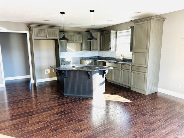 kitchen with dark hardwood / wood-style flooring, sink, a center island, and dark stone counters