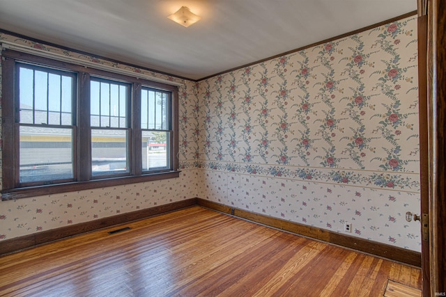 empty room featuring wood-type flooring and crown molding