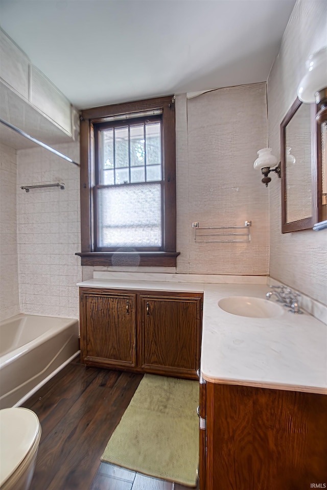 full bathroom with vanity, wood-type flooring, tiled shower / bath combo, and toilet