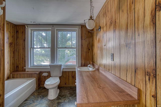 bathroom with wood walls, toilet, a healthy amount of sunlight, and a bath