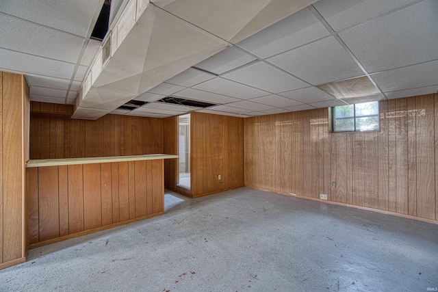 basement with a paneled ceiling and wood walls