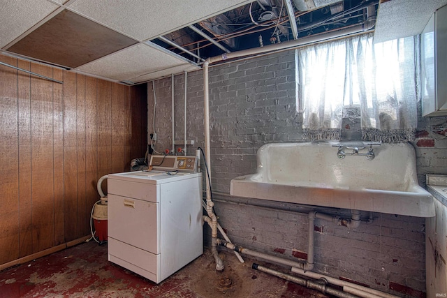 laundry room with wooden walls, sink, and washer / dryer