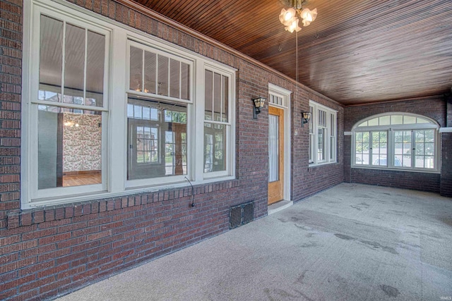 unfurnished sunroom featuring wooden ceiling and a chandelier