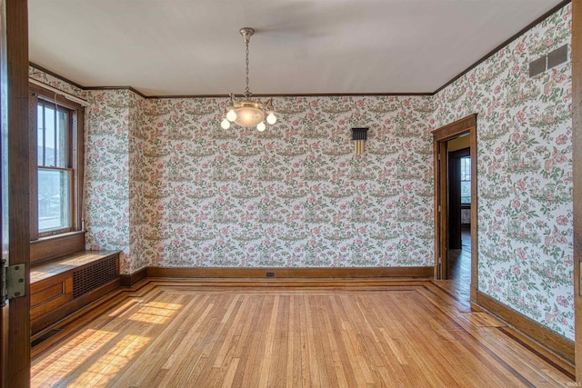 unfurnished dining area featuring light wood-type flooring, an inviting chandelier, and ornamental molding