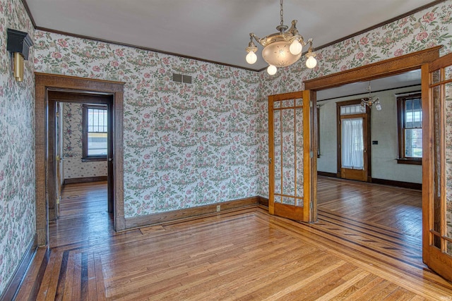 interior space featuring hardwood / wood-style floors, an inviting chandelier, french doors, and ornamental molding