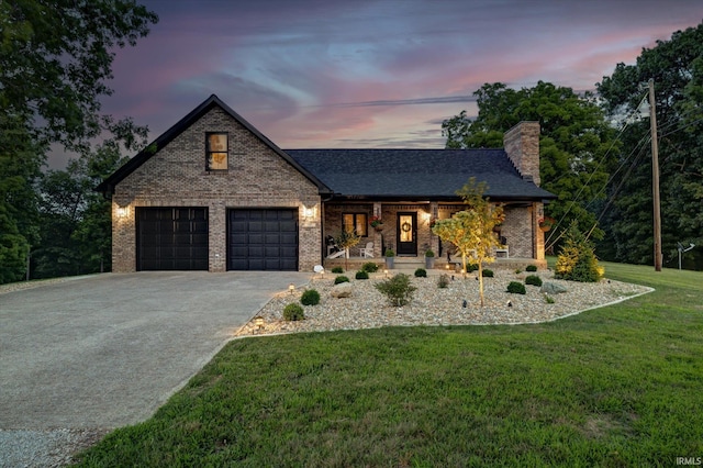 view of front of property with covered porch, a garage, and a lawn