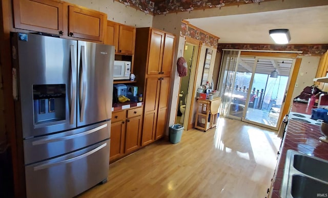 kitchen featuring stainless steel refrigerator with ice dispenser, sink, light hardwood / wood-style flooring, and tile counters