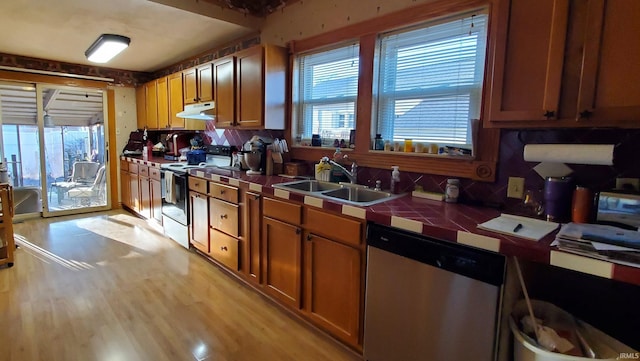 kitchen featuring dishwasher, sink, range with electric stovetop, tile countertops, and light wood-type flooring