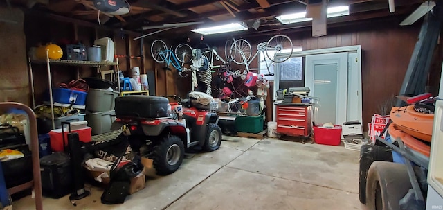 garage featuring wooden walls, a garage door opener, and a workshop area