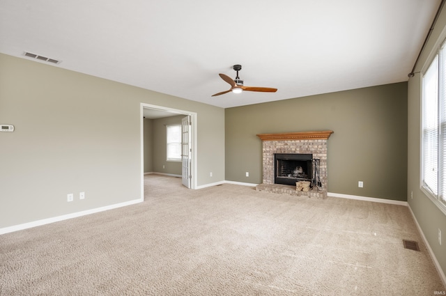 unfurnished living room with ceiling fan, light carpet, and a brick fireplace