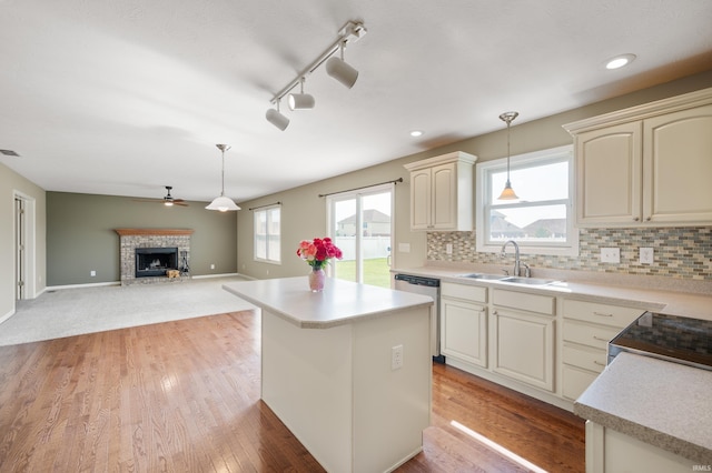 kitchen with sink, light hardwood / wood-style flooring, hanging light fixtures, appliances with stainless steel finishes, and cream cabinetry